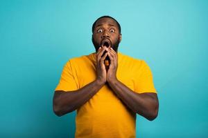 Amazed and shocked expression of a boy over cyan background photo