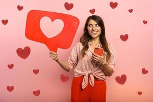 Woman is happy because receives hearts on social network. Pink background photo