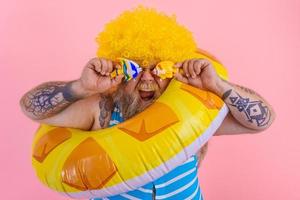 Fat happy man with wig in head is ready to swim with a donut lifesaver photo