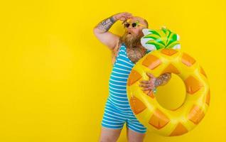 Fat amazed man with wig in head is ready to swim with a donut lifesaver photo