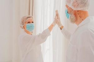 Doctors with mask and face protector give each other a 5 with their hand photo