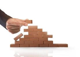 Businessman puts a brick to build a wall. Concept of new business, partnership, integration and startup photo