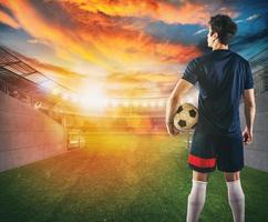 Soccer player ready to play with ball in his hands at the exit of the locker room tunnel photo