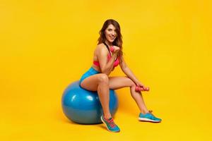 Girl trains with handlebars and gym ball. yellow color background photo