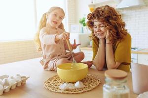 Mother and daughter prepare a cake together in the kitchen photo