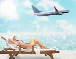 Beautiful girl sitting on a deck chair at the beach at sunset with airplane on background photo