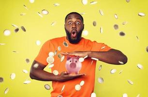 Man under coins rain holds a piggybank. concept of growing investment and deposit profitable. Green background photo