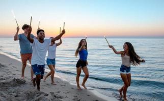 Happy smiling friends running at the beach with sparkling candles photo