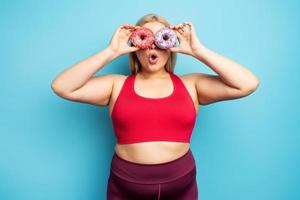 grasa niña piensa a comer rosquillas en lugar de lo hace gimnasia. concepto de indecisión y duda foto