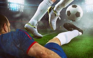 Football scene at night match with close up of two soccer players during a game match at the stadium photo