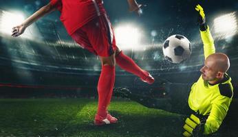 Soccer goalkeeper, in fluorescent uniform, countering the attacker in red uniform photo