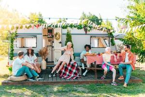 amigos tener un picnic con un camper en un verde prado foto