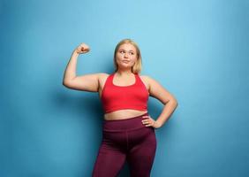 Fat girl does gym at home. thoughtful expression. Cyan background photo