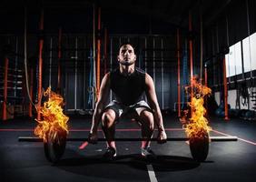 Athletic man works out at the gym with a fiery barbell photo