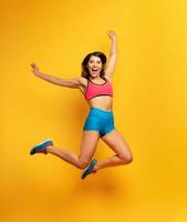 deporte mujer saltos en un amarillo antecedentes. contento y alegre expresión. foto
