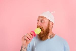 Amazed man with beard and tattoos acts like a little newborn baby with pacifier in hand photo