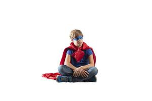 Superhero kid sitting on a wall that dreams. Isolated on white background photo