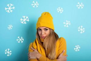 Girl covers herself to avoid catching a cold. Cyan background photo