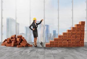 Businesswoman with helmet builds a growing stats bar with bricks photo