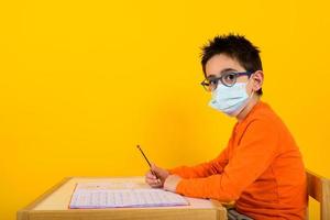 Child at school with face mask for covid-19 coronavirus. yellow background photo