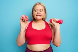 Fat girl thinks to eat donuts instead of does gym. Concept of indecision and doubt photo