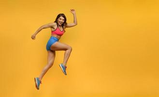 Sport woman runs on yellow background. Happy and joyful expression. photo