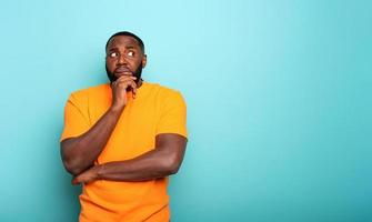 Confuse and pensive expression of a boy . cyan colored background photo