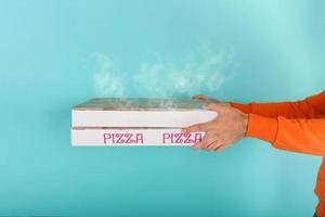 Deliveryman holds bizza boxes ready to be delivered . cyan background photo