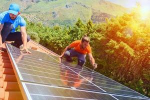 Workers assemble energy system with solar panel for electricity and hot water photo