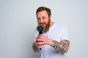 Happy man with beard play with hair dryeras a handgun photo