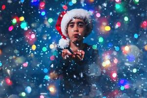 Child with Christmas hat blows to make the snow fly photo