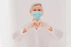 Doctor with mask makes a heart with her hands photo