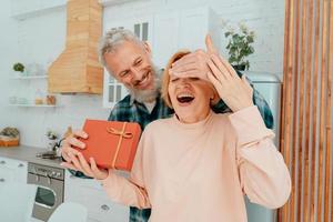 husband gives a gift to her wife at home photo