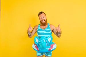 Happy man with inflatable donut with elephant is ready to swim photo