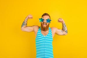 hombre con barba, tatuajes y traje de baño muestra su músculo foto