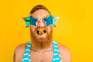 man with beard and sunglasses eats a strawberry photo