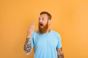 Annoyed man with beard and tattoo yawns with boredom photo