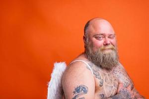 Fat doubter man with beard ,tattoos and wings acts like an angel photo