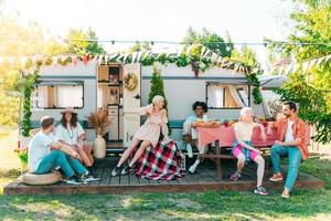 Friends have a picnic with a camper in a green meadow photo