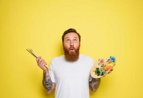 Man with beard and tattoo is ready to draw with brushes photo