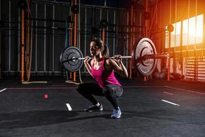 Athletic girl works out at the gym with a barbell photo