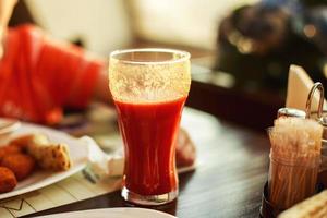 un vaso de tomate jugo en un mesa foto