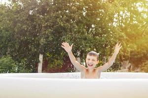 happy boy having fun in the swimming pool with father in the garden at summer photo