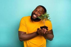 hombre sostiene y toma cuidado de un pequeño árbol foto