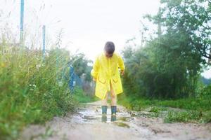 child in rubber boots playing in a puddle photo