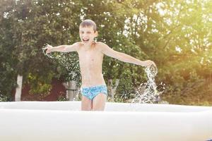 contento chico teniendo divertido en el nadando piscina con padre en el jardín a verano foto