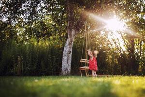 girl in the garden playing with swings. baby playing in the garden photo
