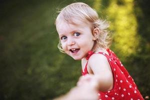 retrato de un pequeño contento muchacha. el niño sostiene el mano de el padre y obras de teatro foto