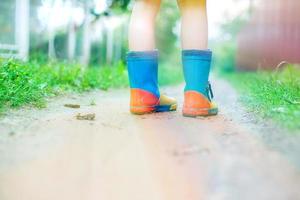 niño en caucho botas caminando exterior. niño pies en un caucho bota foto