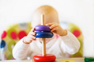 the kid plays the pyramid. child playing with wooden toys photo